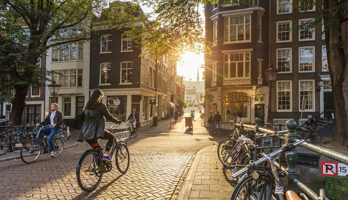 People riding bicycles through downtown Amsterdam. Sunlight and silhouettes
