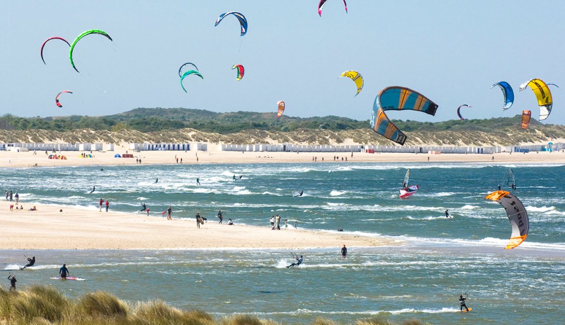 Kitesurfers at sea with beach and beach houses Vrouwenpolder Zeeland