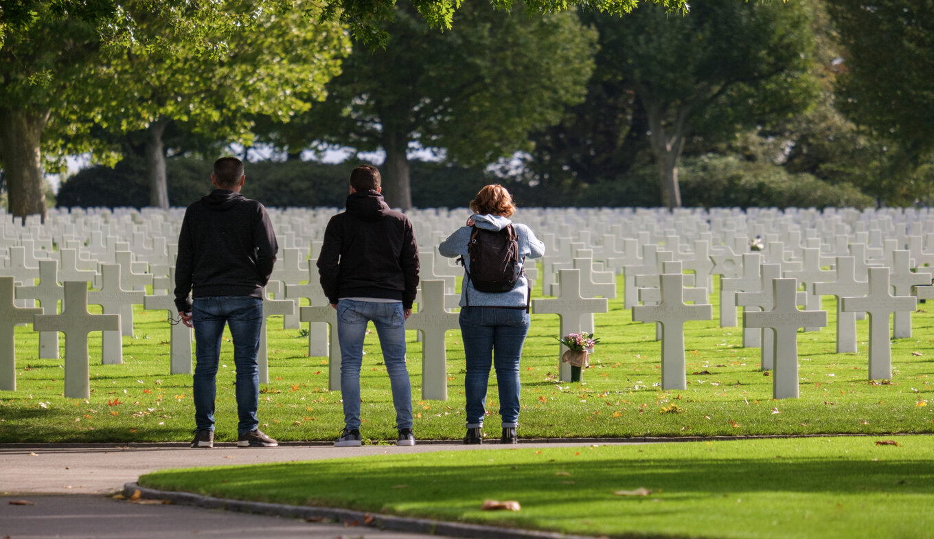 Group people stand still at the graves of the cemetery in Margraten