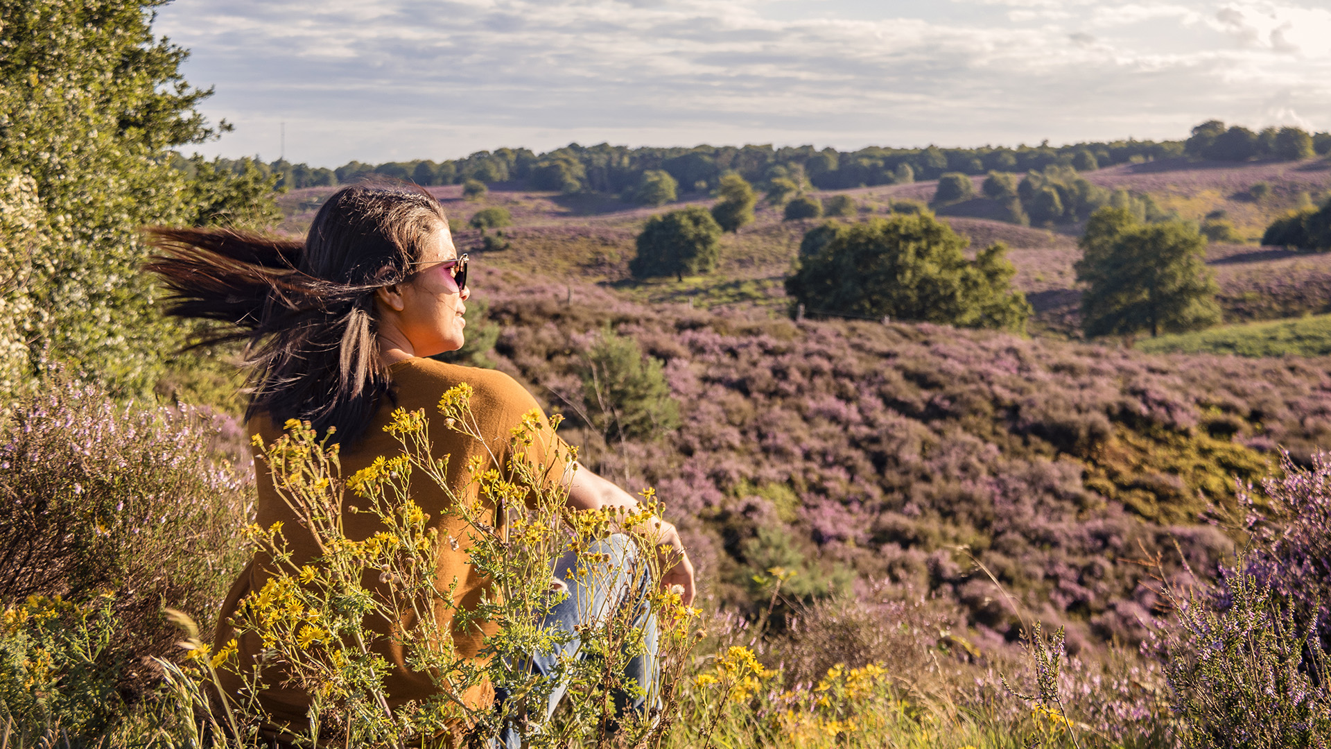 Girl sitting in grasfield looking at Nationalpark Veluwezoom 