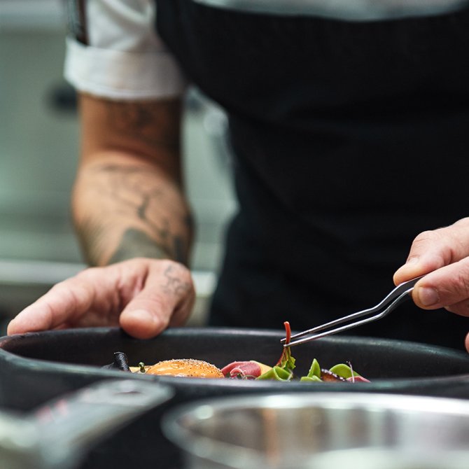 Hands of the chef garnishing food in a restaurant kitchen
