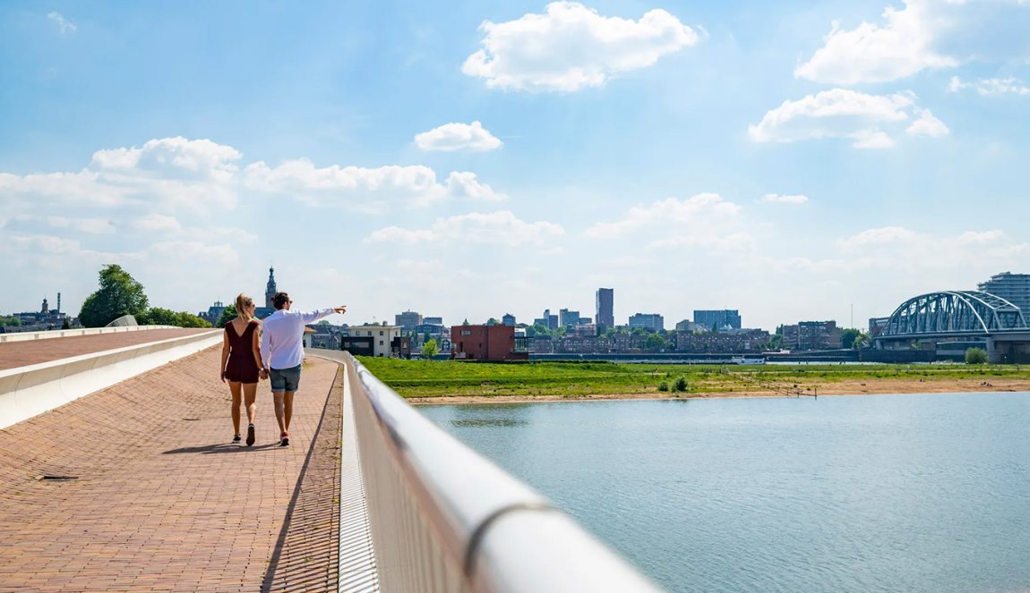 Couple walks across bridge with skyline Veur-Lent Nijmegen