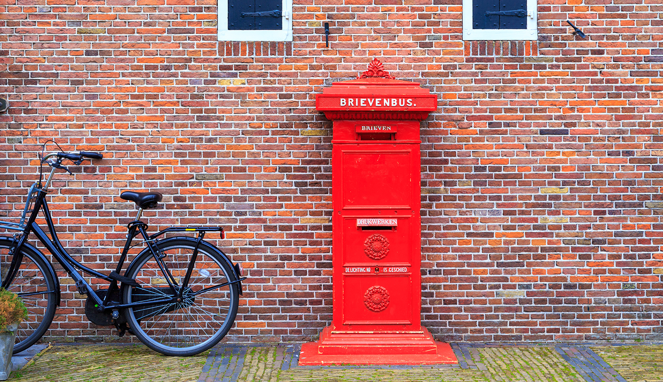 Big red vintage mailbox (brievenbus) against a brick wall
