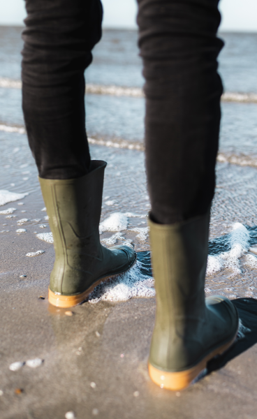 Green rainboots at edge of the sea Green rainboots at edge of the sea