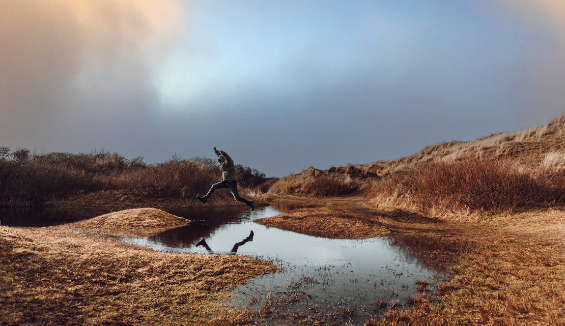 Man jumps over a puddle on Wadden Island Texel