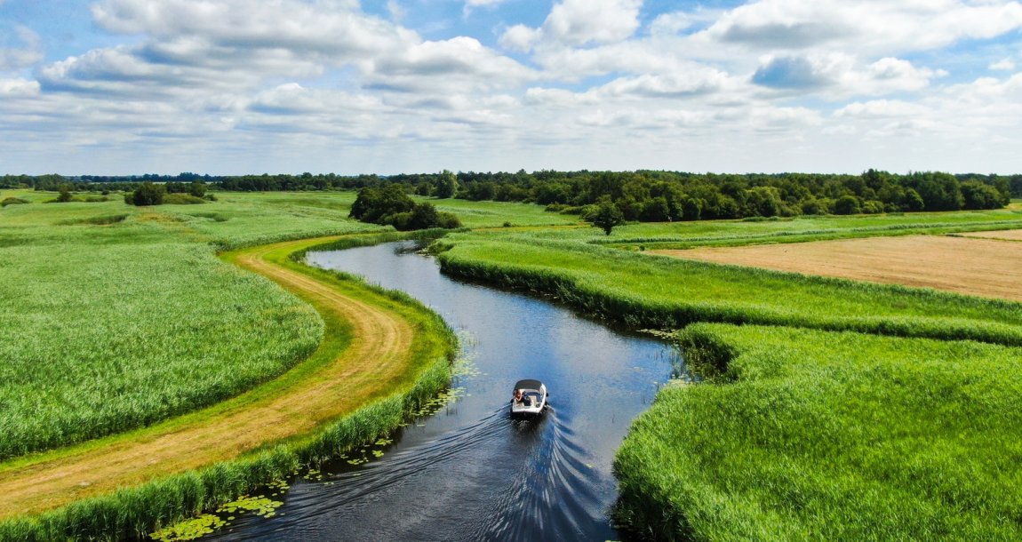 Boat sailing in water through Dutch landscape Boat sailing in water through Dutch landscape